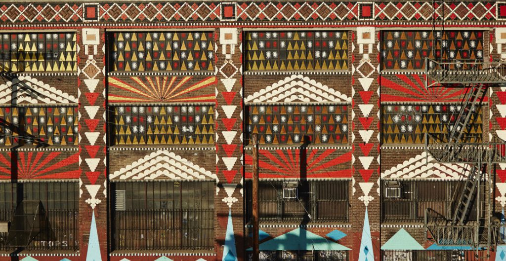 Shrine’s geometric art incorporates the inherent architecture of the JA Roebling’s building to highlight its scale, while maintaining a space for some of the spontaneous street art that inevitably pops up on the Traction Side of the street.