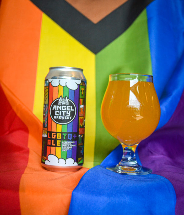 16oz. can of beer next to a pint of beer with a Pride flag in the background