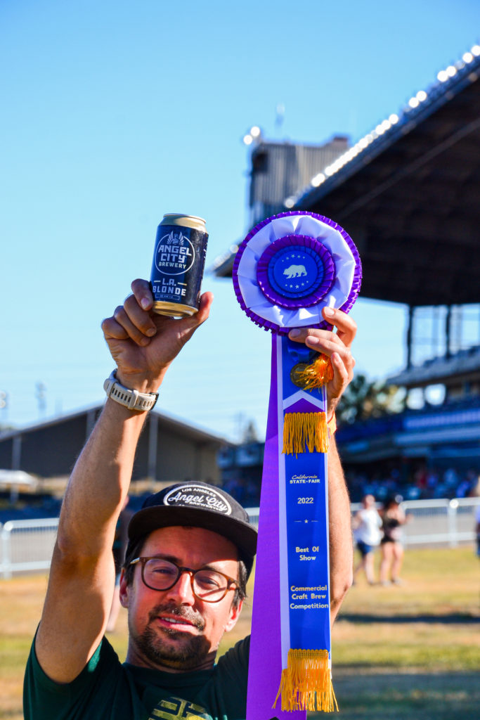 Angel City Head Brewer Layton Cutler hoists "Best of Show" Ribbon with a Can of L.A. Blonde