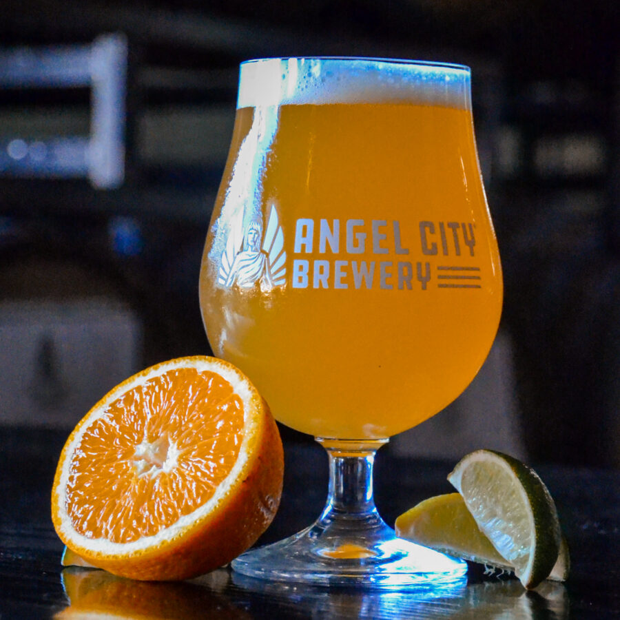 A glass of Citrus Wheat Ale accompanied by slices of orange and lime.